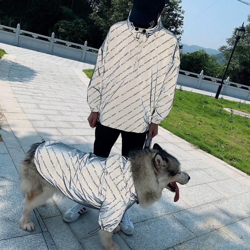 Person and dog wearing matching Pet Shield reflective raincoat, showing versatility for different pets.