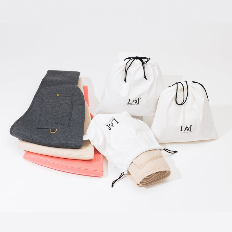 Stack of folded clothes with white drawstring bags featuring 'Laf' branding on a light gray background.