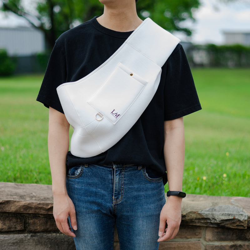 Person wearing a white sling bag over one shoulder outdoors