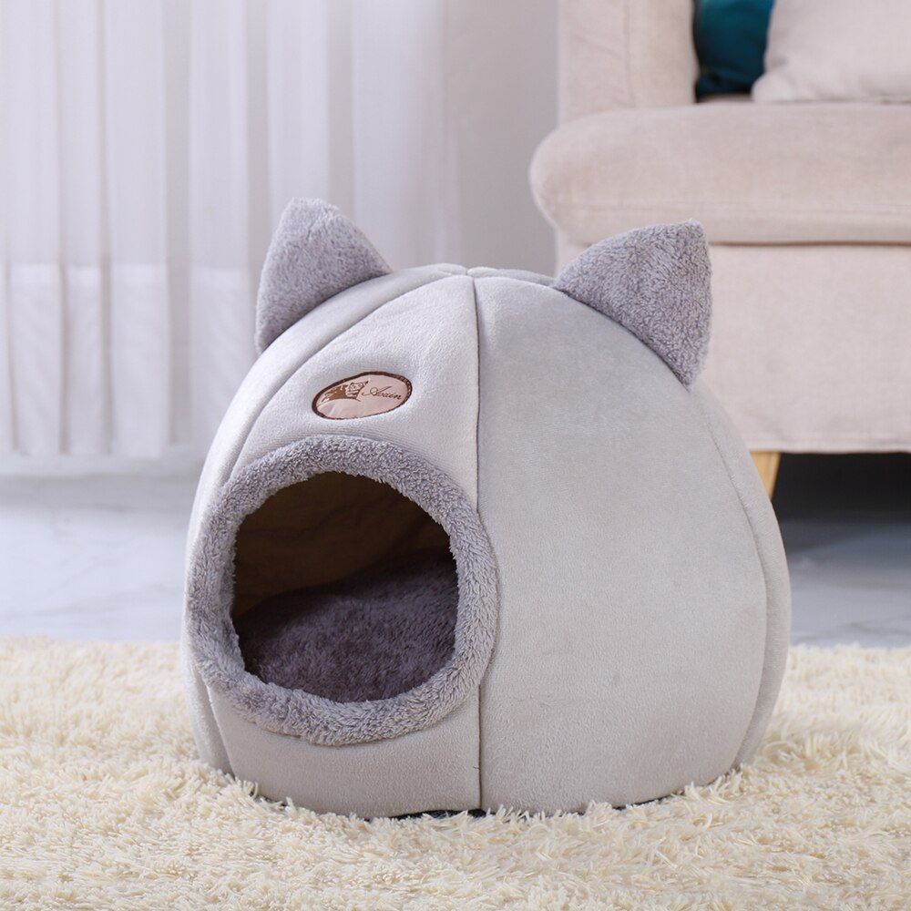 Gray pet bed with cat ears on a carpeted floor.