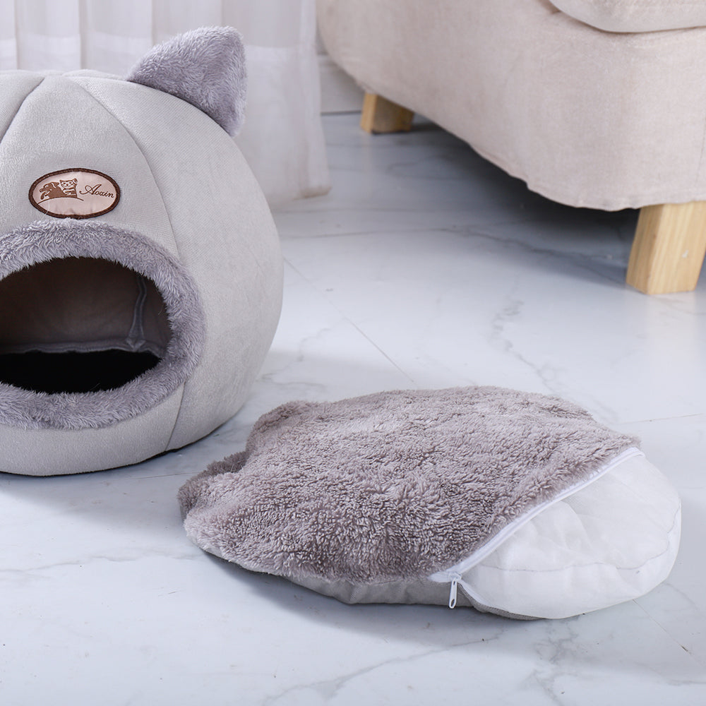 Cat-shaped pet bed and cushion on a light wooden floor.