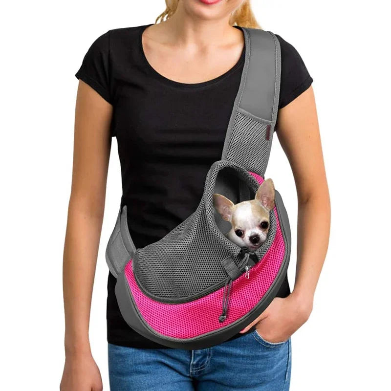 Person holding a gray and pink pet carrier with a small dog inside on a white background