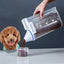 Person pouring dog food from a measuring container into a smaller container, with a dog watching.