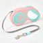 Pink and teal dog leash with a retractable design on a white background