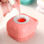 Pink silicone scrubber with a smiley face design being used to clean a red container.