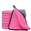 Stack of pink microfiber towels with a gray towel on a white background