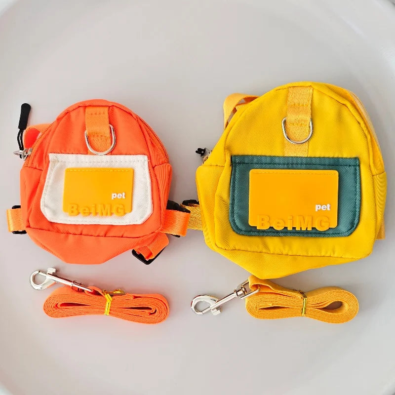 Two dog harnesses, one orange and one yellow, with matching leashes on a light gray background.