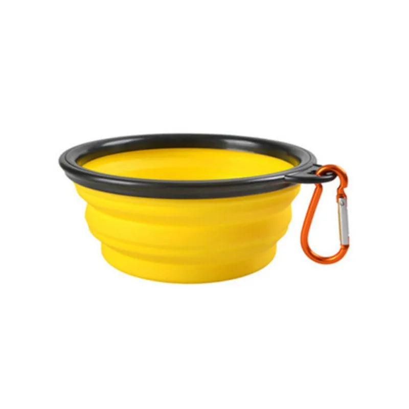Yellow collapsible dog bowl with black rim and orange carabiner on a white background