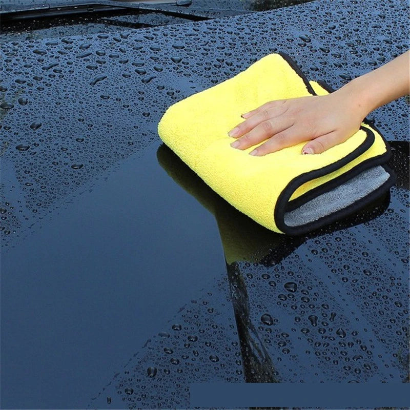 Yellow microfiber cloth on a car windshield with a hand holding it